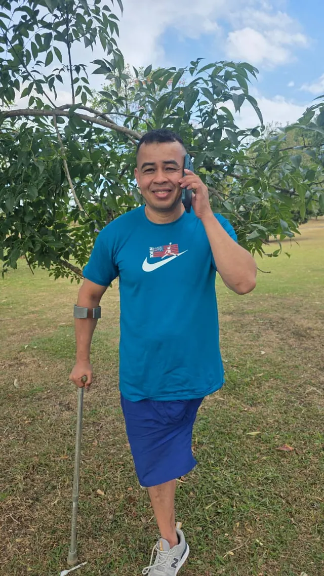 Nando standing in a park using a mobility aid
