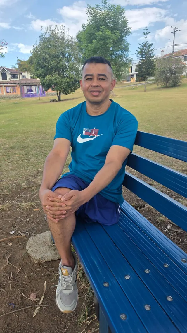 Portrait of Nando seated on a park bench